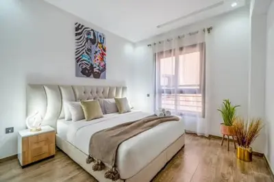 a white bedroom with a large bed and a window at Emplacement idéal fraîcheur garantie, piscine netflix in Marrakech