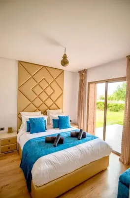 a bedroom with a large bed with blue pillows at Modern 3BR Apartment with Pool & Golf Views in Marrakech