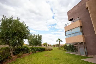 a building with a grass yard next to a building at Modern 3BR Apartment with Pool & Golf Views in Marrakech