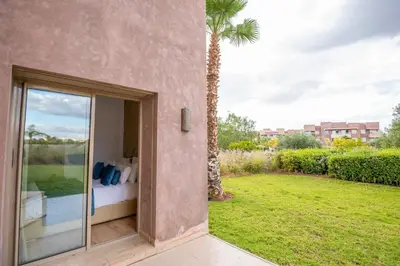 a room with a bed and a view of a yard at Modern 3BR Apartment with Pool & Golf Views in Marrakech
