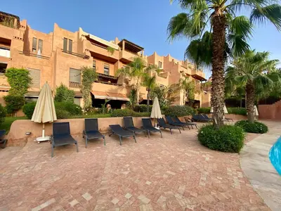 a group of chairs and umbrellas next to a building at Oasis de Charme au coeur de la zone touristique in Marrakech