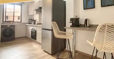 a kitchen with a refrigerator and a counter with chairs at Apartments giliz Marrakech in Marrakech