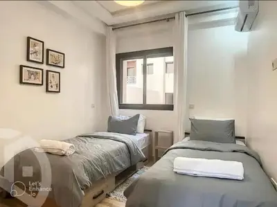 two beds in a room with a window at Apartments giliz Marrakech in Marrakech