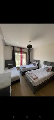 a bedroom with three beds and a chandelier at Location haut standing au cœur de Marrakech in Marrakech
