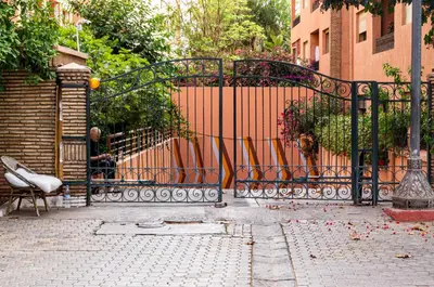 a man sitting on a bench in front of a gate at Appartement 2 bedroom Babylone center in Marrakech