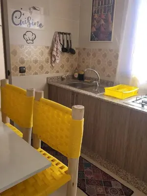 a kitchen with a sink and a table with yellow chairs at Au cœur de l orient Marrakech in Marrakech