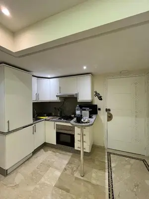 a kitchen with white cabinets and a stove top oven at Guéliz Bright apartment with pools in Marrakech