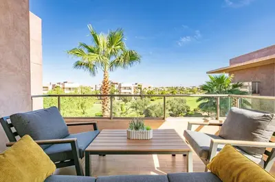 a patio with a table and chairs and a palm tree at Spacious Apartment, Golf & Pool in Marrakech
