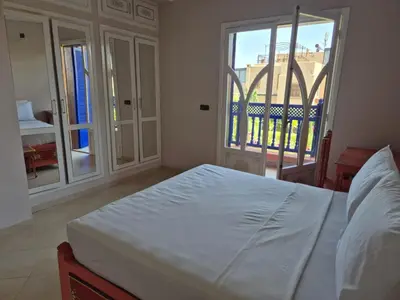 a bedroom with a white bed and a balcony at Villa Kaina in Marrakech