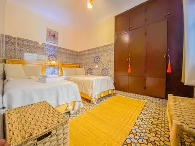 a bedroom with two beds and a yellow rug at Dar AINA in Marrakech