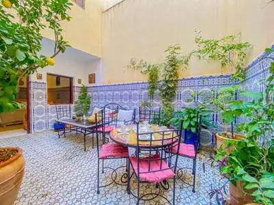 a patio with tables and chairs and potted plants at Dar AINA in Marrakech