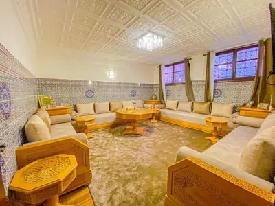 a living room with couches and tables and windows at Dar AINA in Marrakech