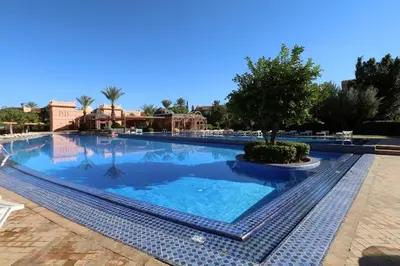 a large swimming pool with a tree in the middle at Le Palmito - 2BDR - Private Garden - Pool in Marrakech