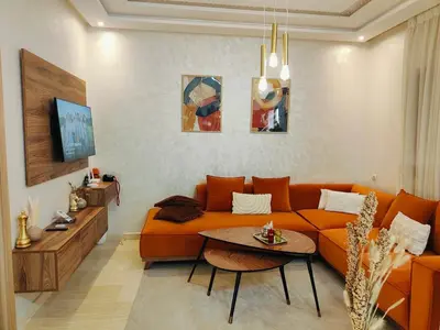 a living room with an orange couch and a table at Appart chaleureux et calme, fibre et Netflix in Marrakech