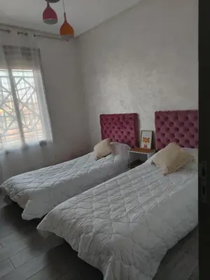 a bedroom with two beds and a window and two chairs at Appartement luxueux à louer in Marrakech