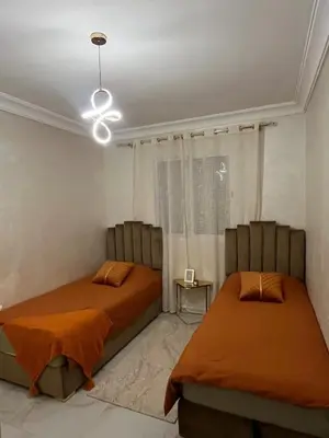 a bedroom with two beds and a chandelier at Appartement Cosy Marrakech in Marrakech