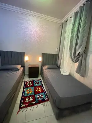a bedroom with two beds and a rug on the floor at Airport Apartment in Marrakech