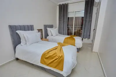 two beds with yellow sheets in a room with a window at appartement majorelle in Marrakech