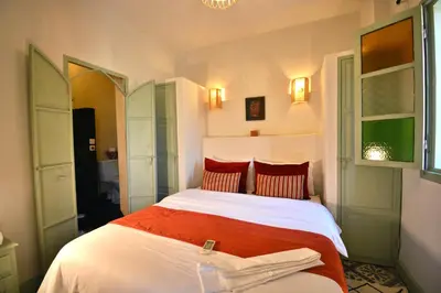 a bedroom with a bed with red and white sheets at Beldi House in Marrakech