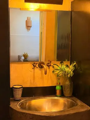 a sink with a vase and a mirror above it at Beldi House in Marrakech