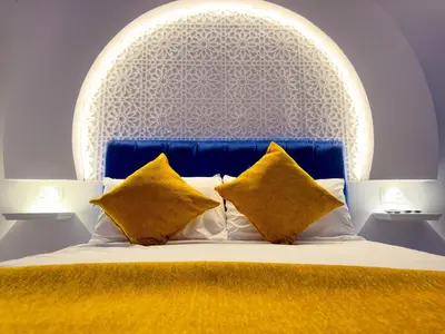 a bed with a blue headboard and two yellow pillows at Suite Majorelle l Gueliz,balcon,clim, Netflix,WiFi in Marrakech