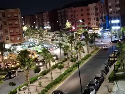 a city street at night with cars and palm trees at Apartment heart of Marrakech in Marrakech