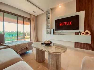 a living room with a tv and a table at Luxury Apartment in Prestigia Marrakech in Marrakech