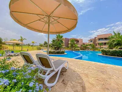 two chairs and an umbrella next to a swimming pool at Luxury Apartment in Prestigia Marrakech in Marrakech