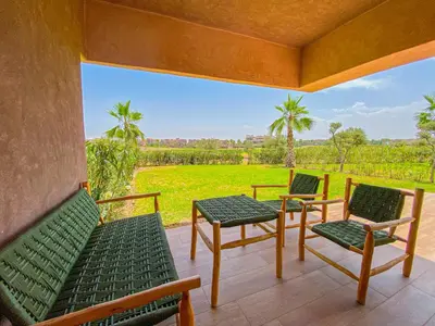 a porch with green chairs and a view of a field at Luxury Apartment in Prestigia Marrakech in Marrakech