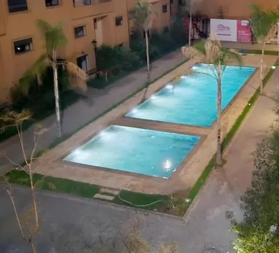 an overhead view of two swimming pools with palm trees at Cozy Family Apartment 2BR Pool Parking Gueliz Marrakesh in Marrakech