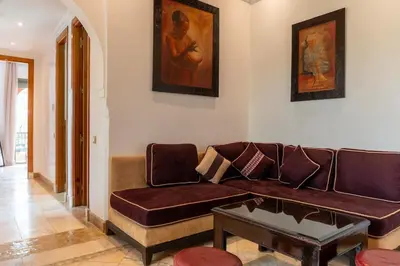 a living room with a brown couch and a table at Palmeraie vintage apartment with pool in Marrakech
