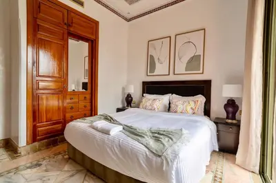 a bedroom with a large bed with a wooden door at Palmeraie vintage apartment with pool in Marrakech