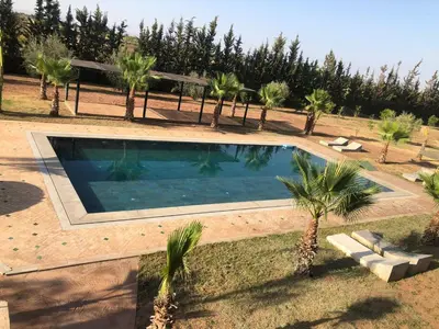 a swimming pool in a yard with palm trees at Dar AZZARO in El Rhechat