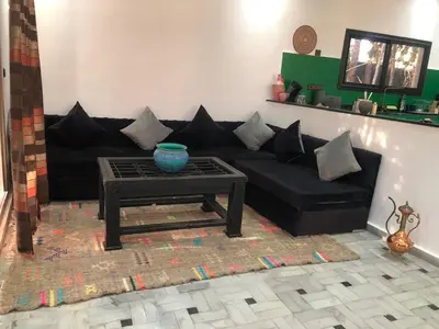 a living room with a black couch and a table at Dar AZZARO in El Rhechat