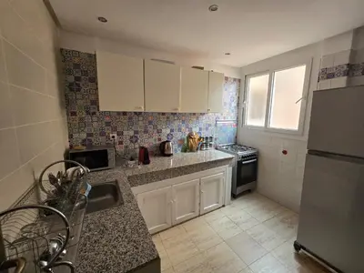 a kitchen with white cabinets and a sink and a refrigerator at Appartement Moderne Gueliz in Marrakech