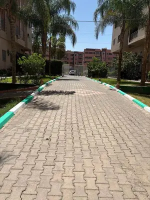 a cobblestone street with palm trees and buildings at Gueliz modern in Marrakech