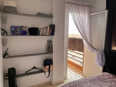 a bedroom with a bed and bookshelves and a window at Apparemment à Marrakech in Marrakech