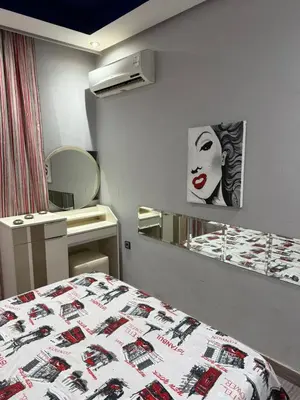 a bedroom with a bed and a mirror with a woman on the wall at Bssatin gueliz in Marrakech