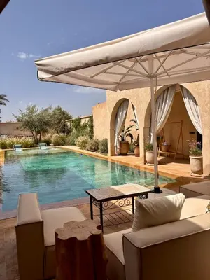 a swimming pool with a table and an umbrella at Villa Cactus & chill - Breakfast included! in Marrakech