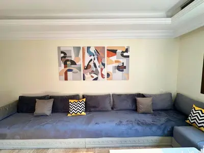 a blue couch in a living room with paintings on the wall at Modern Apartment in Centre of Marrakech For Friends & Familie in Marrakech