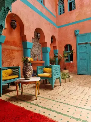 a courtyard with chairs and a vase on a table at Riad Massin Marrakech in Marrakech