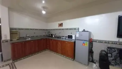 a kitchen with a refrigerator and wooden cabinets at Appartement 2 Chambres à Belbekkar, Marrakech in Marrakech