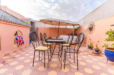 a patio with a table and chairs and an umbrella at Riad Hbibti Authentic Moroccan Stay with Rooftop Jacuzzi in Marrakech