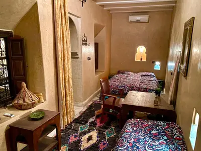 a room with two beds and a table in a room at Riad Sylvia in Marrakech