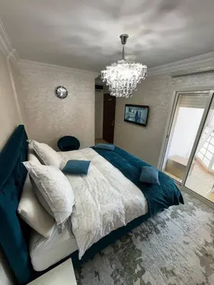 a bedroom with a large bed and a chandelier at شقة بغرفة معيشة مغربية in Marrakech