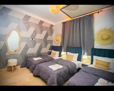 a bedroom with three beds and a mirror at Spacious Moroccan Stay, Near Airport in Marrakech