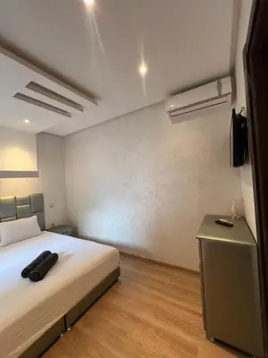 a bedroom with a bed and a tv on a wall at Appartement neuf & moderne avec clim, piscine & balcon,Proche Jemaa el-Fna & Guéliz in Marrakech