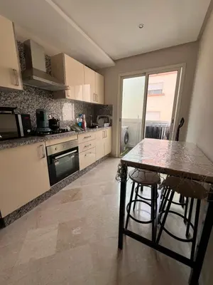 a kitchen with a table and chairs in it at Appartement neuf & moderne avec clim, piscine & balcon,Proche Jemaa el-Fna & Guéliz in Marrakech