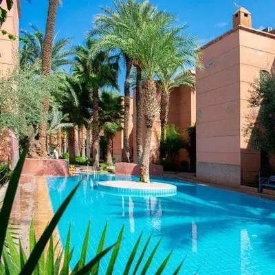 a swimming pool with palm trees in a resort at Appartement neuf bien situé in Marrakech