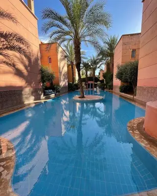 a swimming pool with a palm tree in the middle at Appartement neuf bien situé in Marrakech